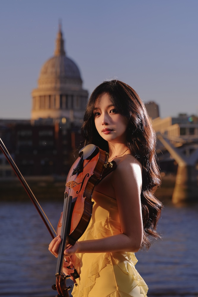 Venice holding a violin by the River Thames