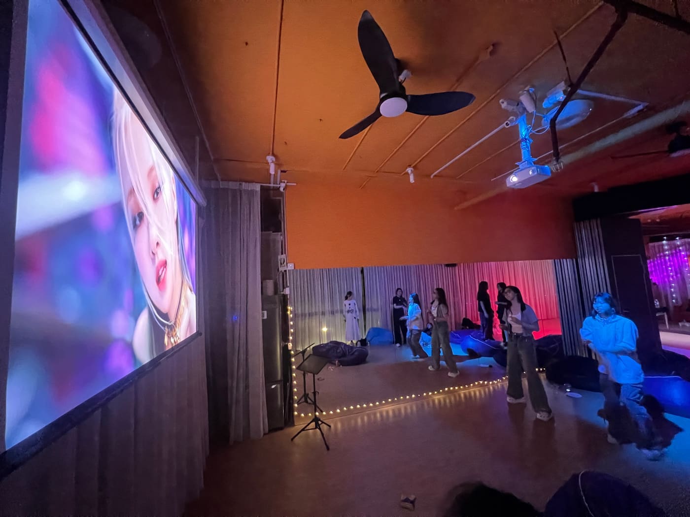 Dancers following a K-pop music video on the big screen at night