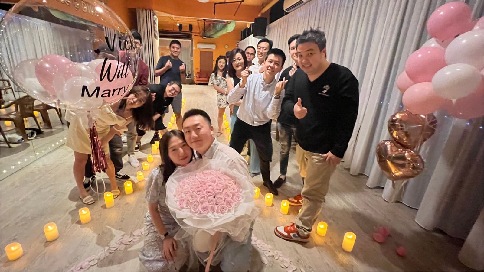 A candlelit celebration at the venue — a couple with roses and cheering friends