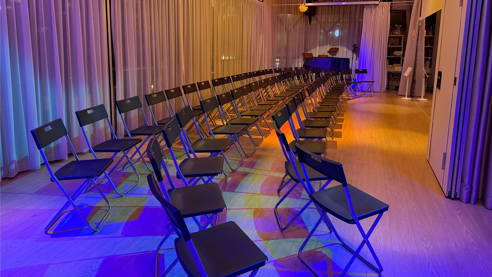The venue arranged for a choir performance — curved rows of seating under colourful lighting